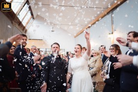   At La Factory in Thizy-les-Bourgs, Rhône, France, the couple celebrates their wedding exit beneath a cascade of confetti and joyful cheers from friends and family.